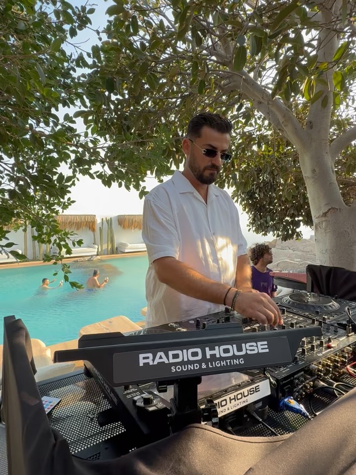 A DJ guy playing near the pool in mykonos with Pioneer Rmx1000