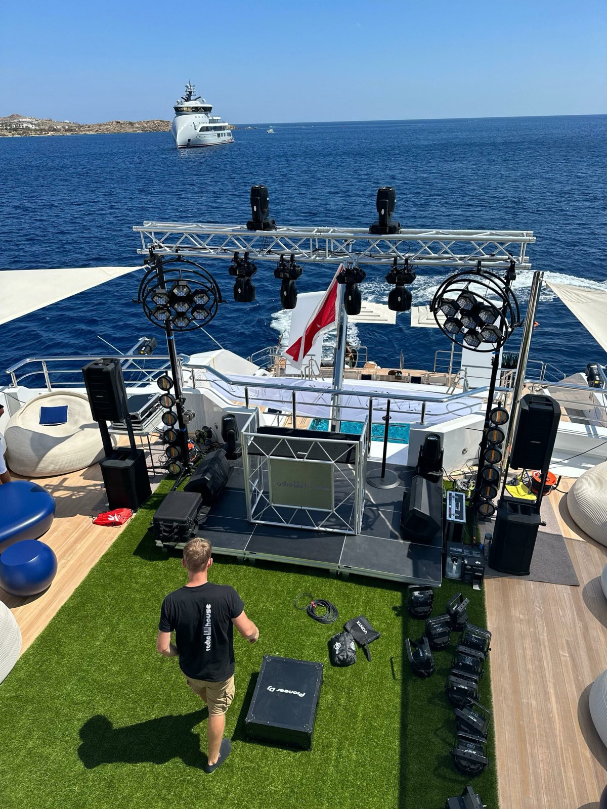 RadioHouse technician setting up a DJ stage with truss, lights and speakers on a yacht aft deck in Mykonos
